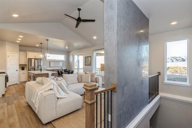 living room featuring ceiling fan, light hardwood / wood-style flooring, and vaulted ceiling