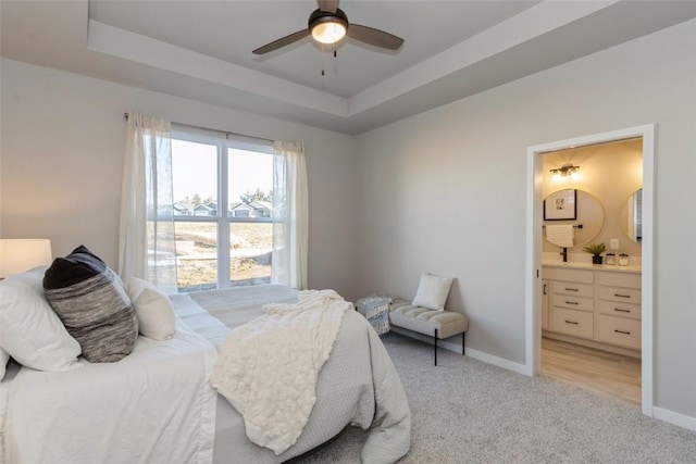 carpeted bedroom featuring ensuite bathroom, a raised ceiling, and ceiling fan