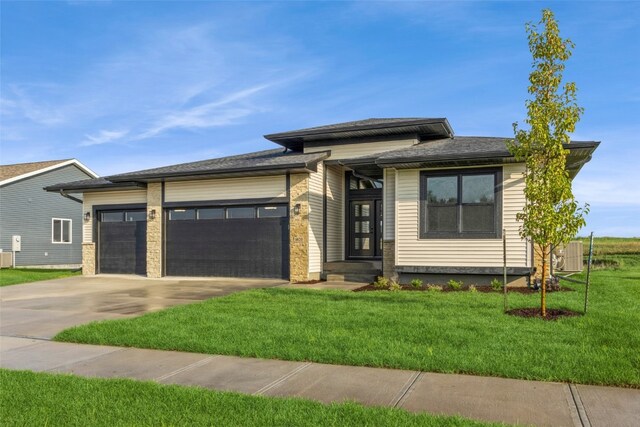 prairie-style house with a front lawn, a garage, and cooling unit