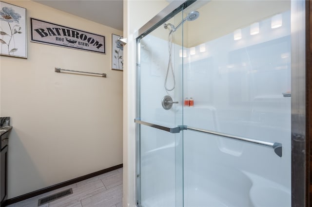 bathroom featuring hardwood / wood-style floors, an enclosed shower, and vanity