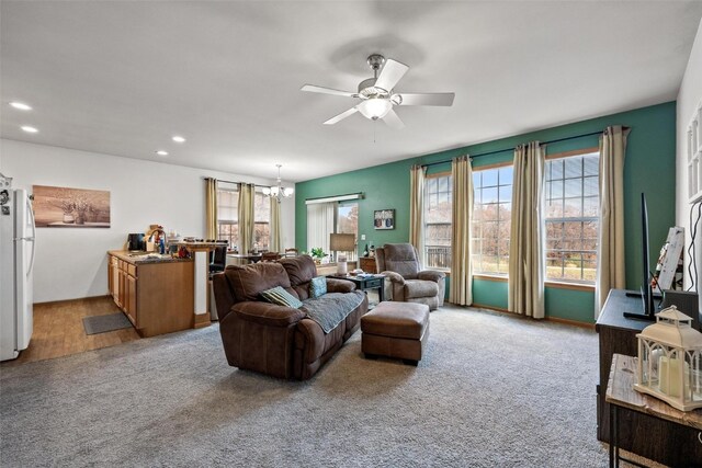 living room featuring ceiling fan with notable chandelier, light carpet, and a healthy amount of sunlight