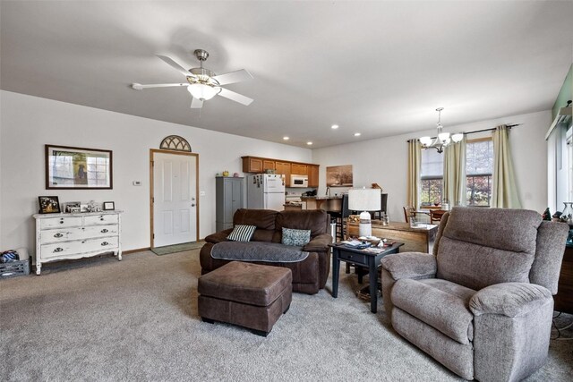 carpeted living room featuring ceiling fan with notable chandelier