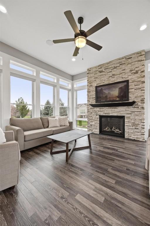 living room with a fireplace, dark wood-type flooring, and ceiling fan