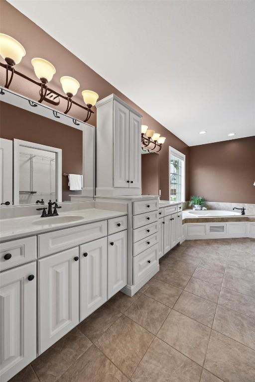 bathroom featuring vanity, a chandelier, tile patterned floors, and a bathing tub