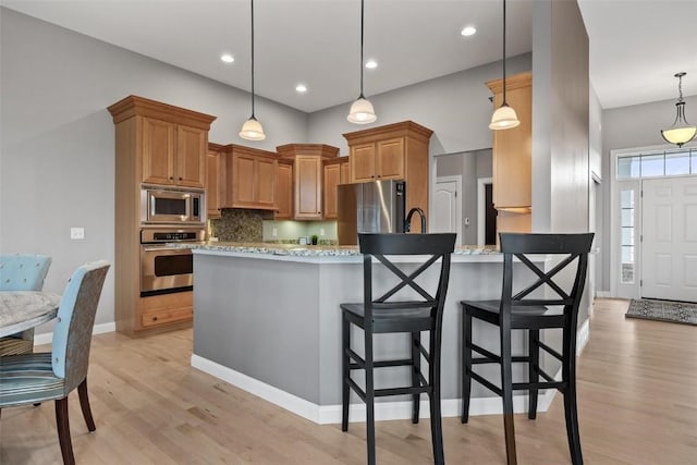 kitchen with decorative light fixtures, light stone countertops, and stainless steel appliances