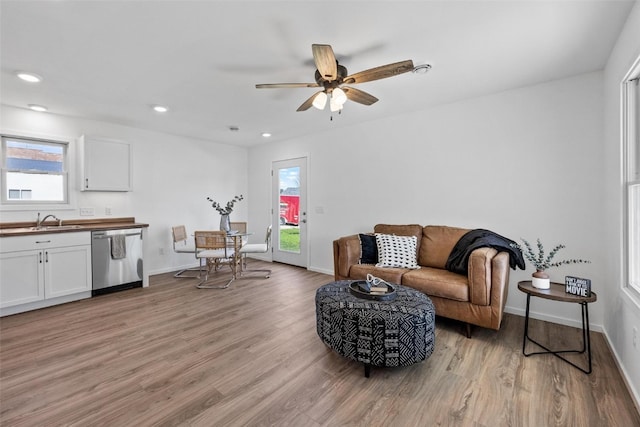 living room featuring light wood-type flooring, a wealth of natural light, and sink