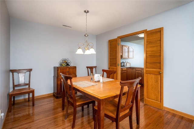 dining area featuring wood-type flooring and a notable chandelier