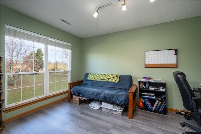 bedroom with a textured ceiling, hardwood / wood-style flooring, and track lighting