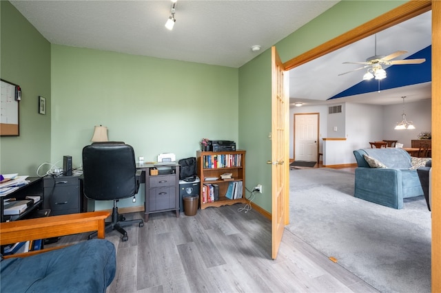 office area with a textured ceiling, light wood-type flooring, lofted ceiling, and ceiling fan