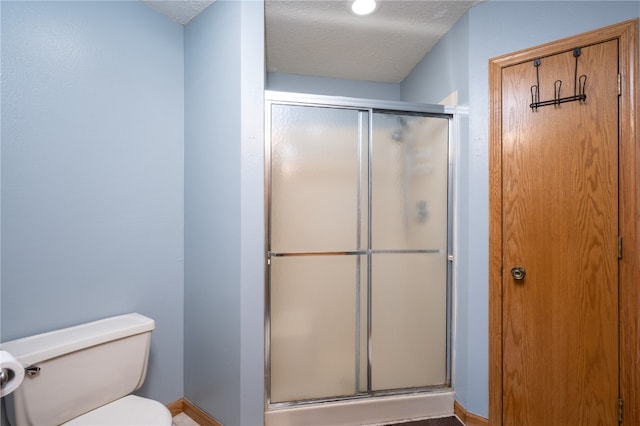 bathroom with an enclosed shower, a textured ceiling, and toilet