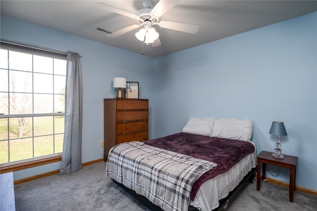 carpeted bedroom featuring a textured ceiling, multiple windows, and ceiling fan