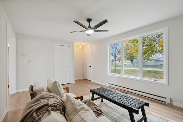 living room with a healthy amount of sunlight, light wood-type flooring, and a baseboard heating unit