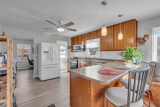 kitchen with plenty of natural light, light hardwood / wood-style flooring, appliances with stainless steel finishes, and tasteful backsplash