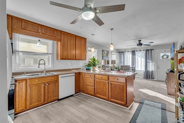 kitchen featuring white dishwasher, sink, light hardwood / wood-style flooring, and kitchen peninsula