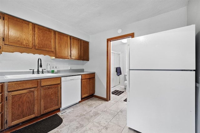 kitchen featuring white appliances, a textured ceiling, and sink