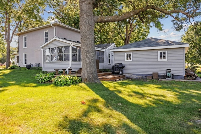 rear view of property with a deck, a sunroom, a yard, and central AC