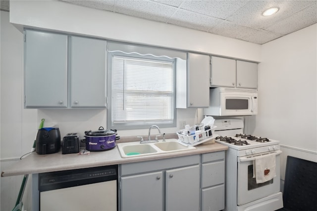 kitchen featuring gray cabinets, a drop ceiling, white appliances, and sink