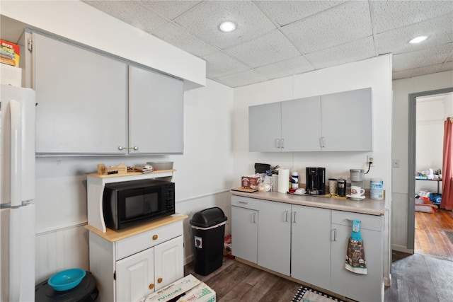 kitchen with a paneled ceiling, white fridge, and dark hardwood / wood-style flooring