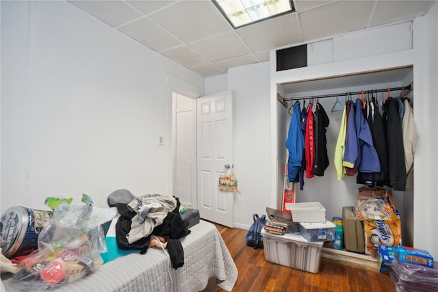 bedroom featuring a paneled ceiling, hardwood / wood-style flooring, and a closet