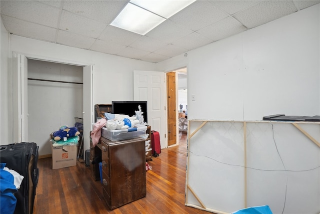 bedroom with dark hardwood / wood-style floors, a closet, and a drop ceiling