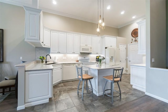 kitchen with a breakfast bar, white cabinets, and white appliances