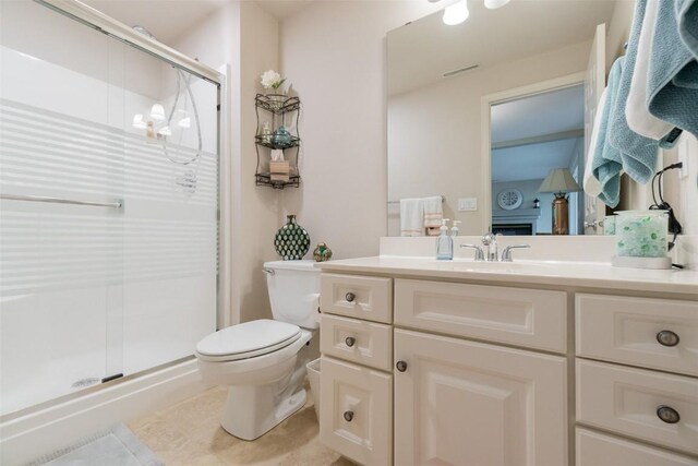 bathroom featuring tile patterned floors, vanity, toilet, and a shower with shower door