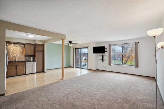 unfurnished living room featuring light colored carpet, ceiling fan, and sink