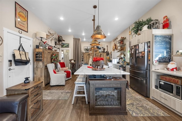 kitchen with a breakfast bar, appliances with stainless steel finishes, dark hardwood / wood-style floors, and pendant lighting