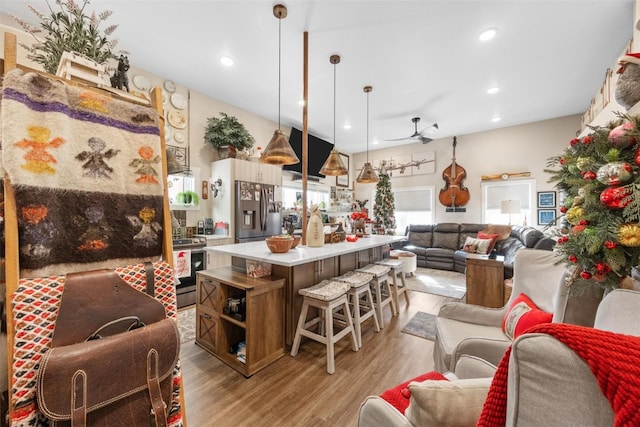 kitchen featuring stainless steel appliances, ceiling fan, pendant lighting, a center island, and light hardwood / wood-style floors