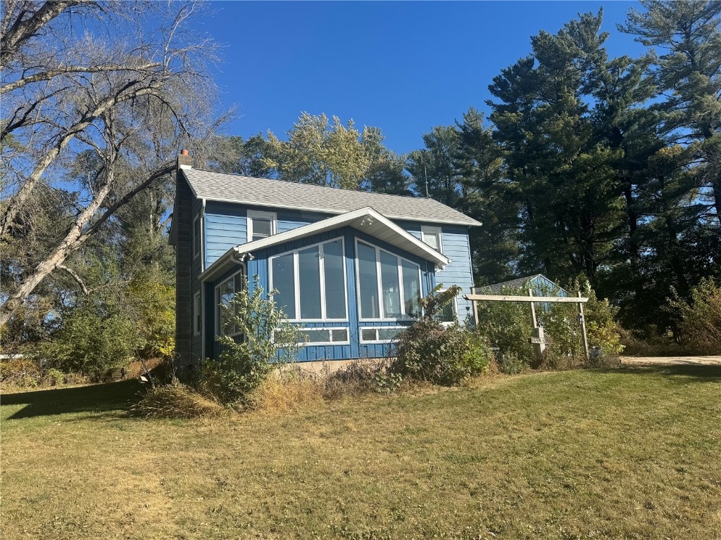 view of side of home featuring a sunroom and a yard