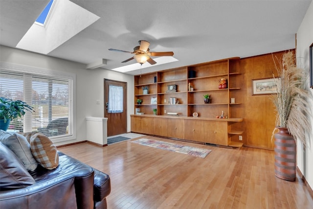 living room with ceiling fan, light wood-type flooring, and a textured ceiling