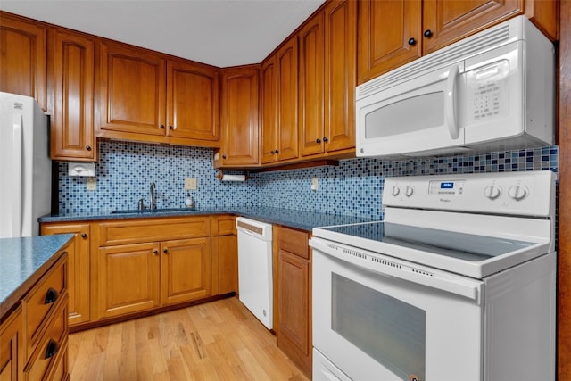 kitchen featuring decorative backsplash, sink, light hardwood / wood-style floors, and white appliances