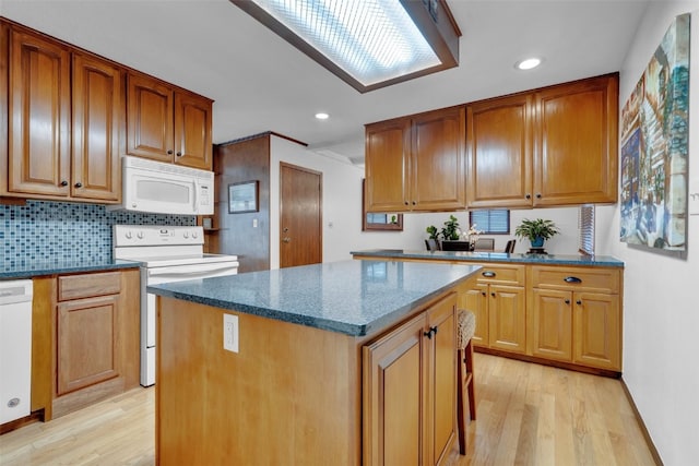 kitchen featuring a center island, backsplash, dark stone counters, light hardwood / wood-style floors, and white appliances