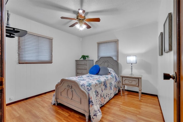 bedroom with ceiling fan, light wood-type flooring, and a textured ceiling