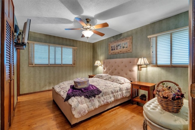 bedroom with multiple windows, ceiling fan, a textured ceiling, and light wood-type flooring