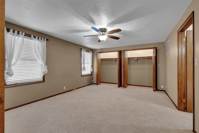 unfurnished bedroom with a closet, a textured ceiling, light colored carpet, and ceiling fan