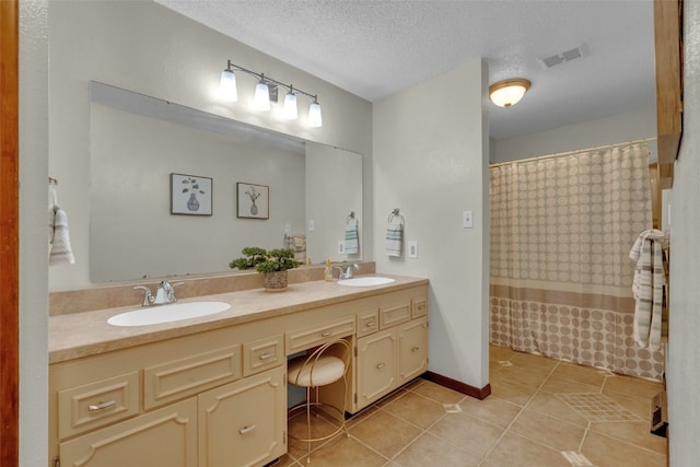 bathroom featuring tile patterned floors, vanity, a textured ceiling, and walk in shower