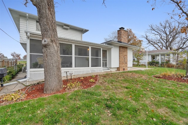 rear view of property featuring a sunroom and a lawn