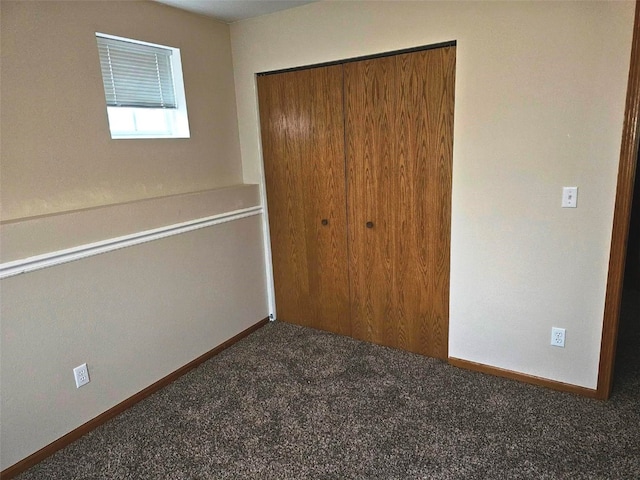 unfurnished bedroom featuring dark carpet and a closet