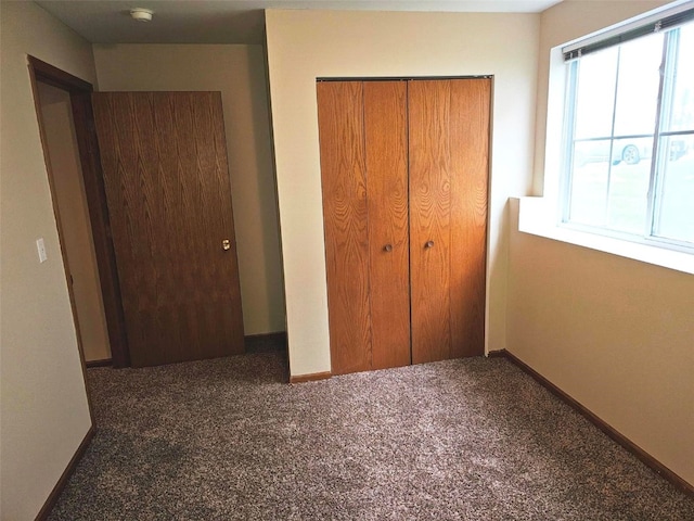 unfurnished bedroom featuring a closet and dark carpet