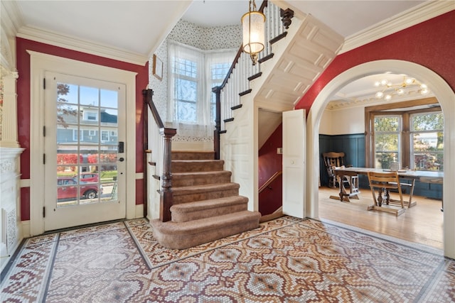 foyer with ornamental molding, a healthy amount of sunlight, and wood-type flooring