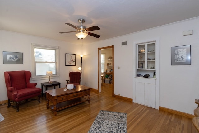 sitting room with ceiling fan, crown molding, and hardwood / wood-style flooring