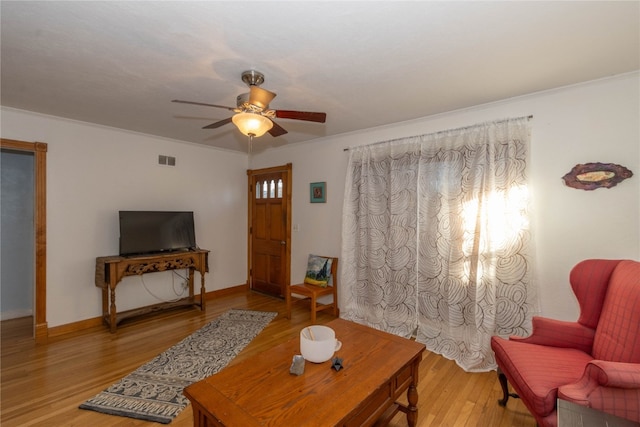 living room with light wood-type flooring, ceiling fan, and crown molding