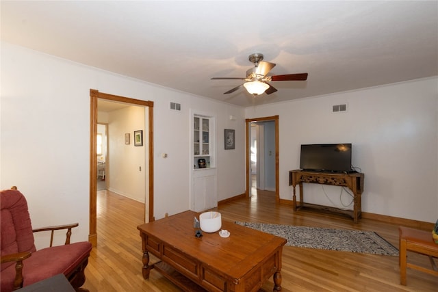 living room featuring light wood-type flooring, ceiling fan, and ornamental molding