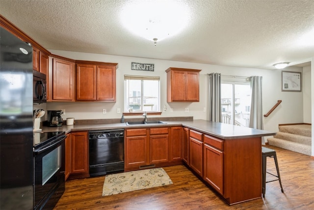 kitchen featuring black appliances, plenty of natural light, kitchen peninsula, and sink