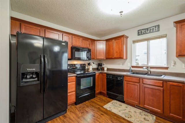 kitchen featuring sink, a textured ceiling, dark hardwood / wood-style flooring, and black appliances