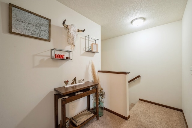 hall with a textured ceiling and light colored carpet