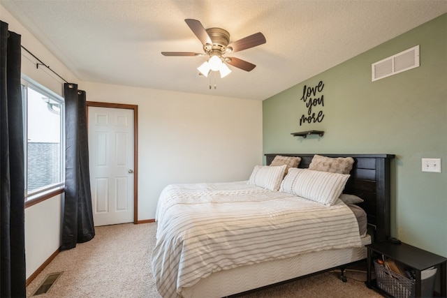 bedroom featuring ceiling fan, light colored carpet, and a textured ceiling