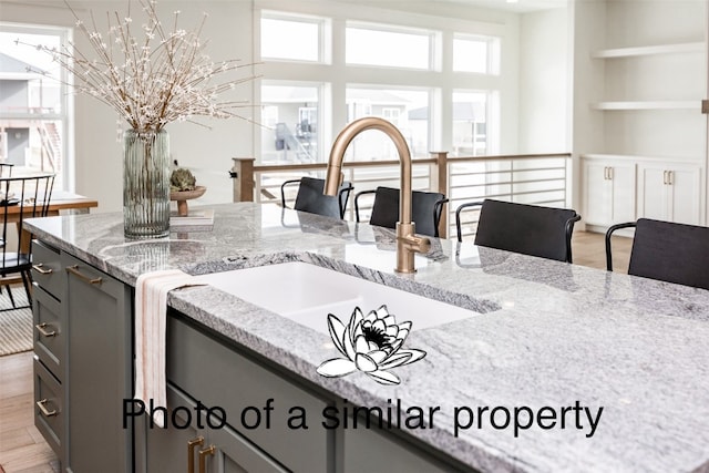 kitchen featuring light stone countertops, sink, and light hardwood / wood-style flooring