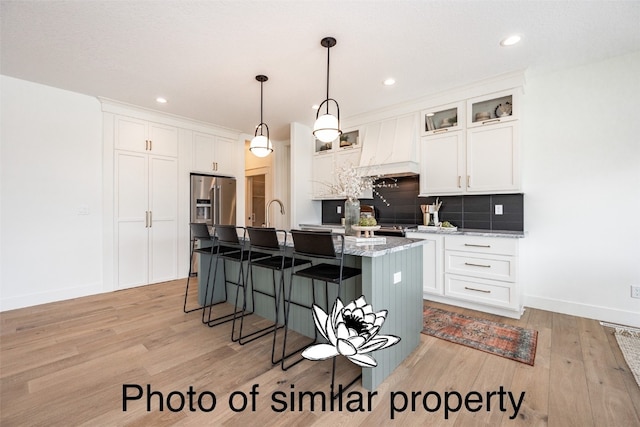 kitchen with a center island with sink, white cabinetry, and light wood-type flooring